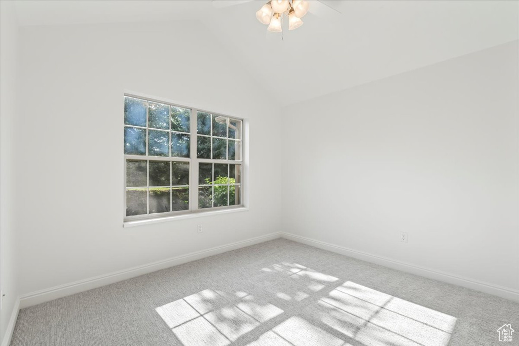 Spare room featuring carpet, ceiling fan, and vaulted ceiling