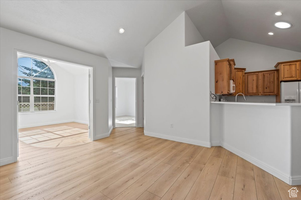 Unfurnished living room featuring vaulted ceiling, light wood-style floors, and recessed lighting