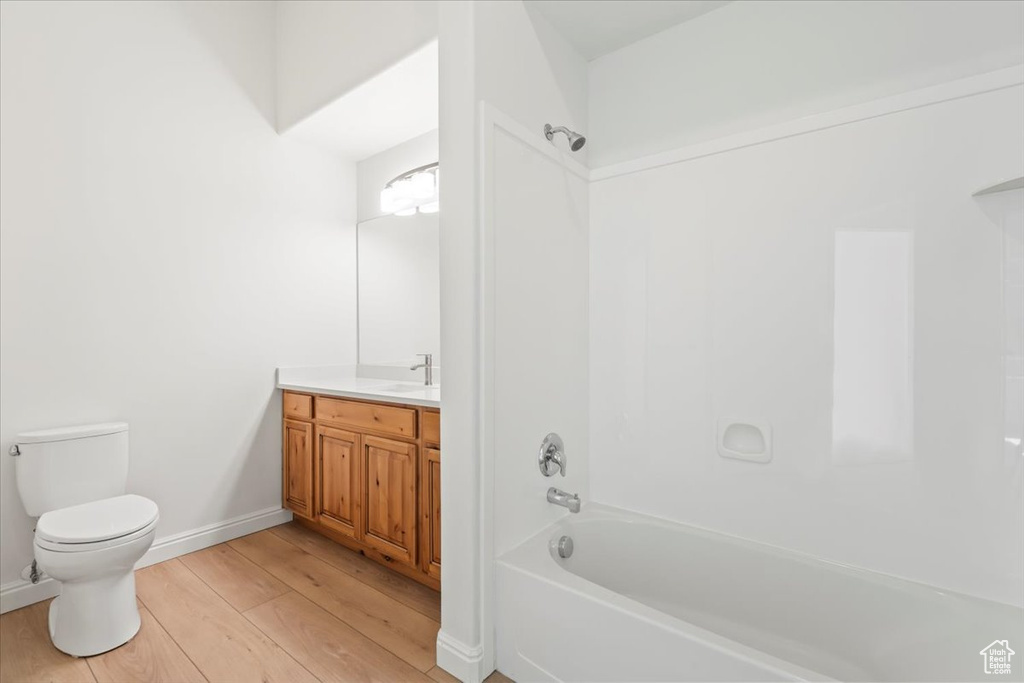 Full bathroom featuring wood finished floors, vanity, and shower / washtub combination