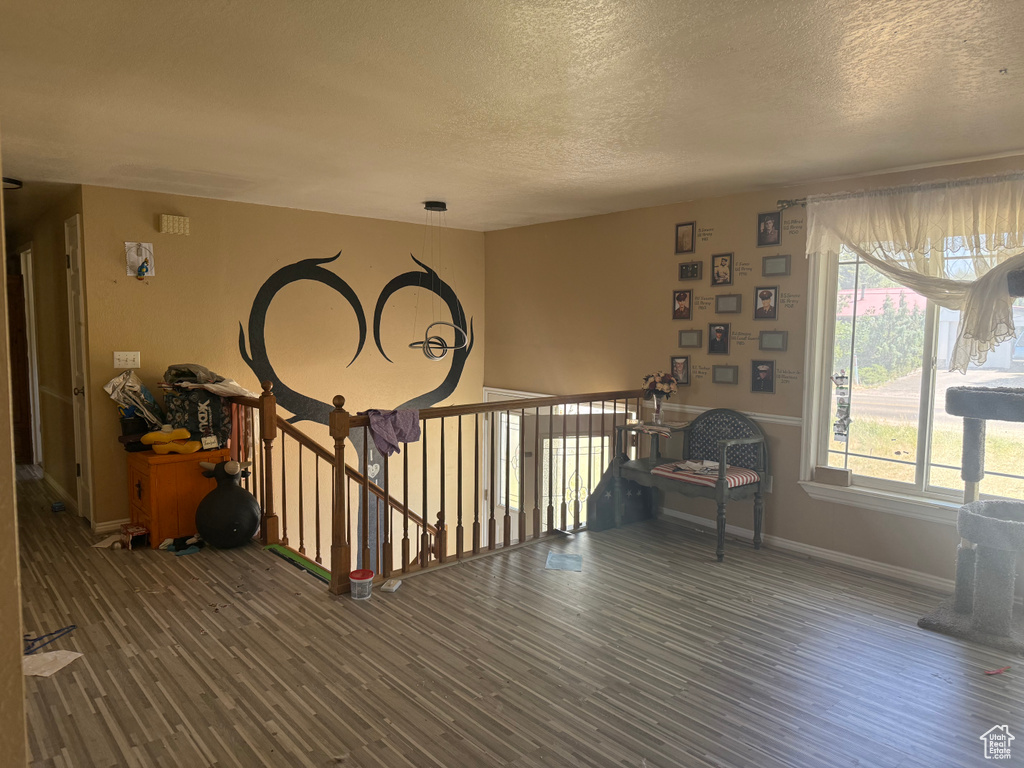 Sitting room with wood finished floors, a textured ceiling, and an upstairs landing