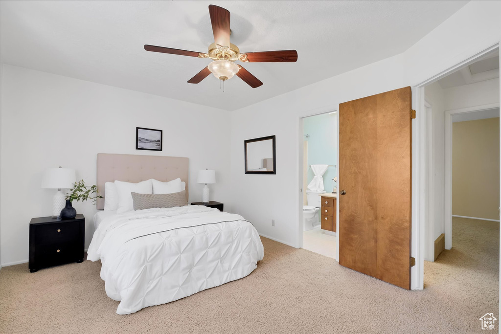 Bedroom featuring light colored carpet, ensuite bathroom, and ceiling fan