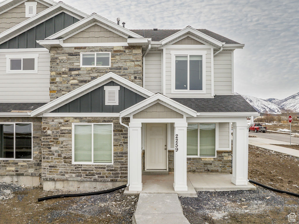 Craftsman house with stone siding, roof with shingles, a mountain view, and board and batten siding