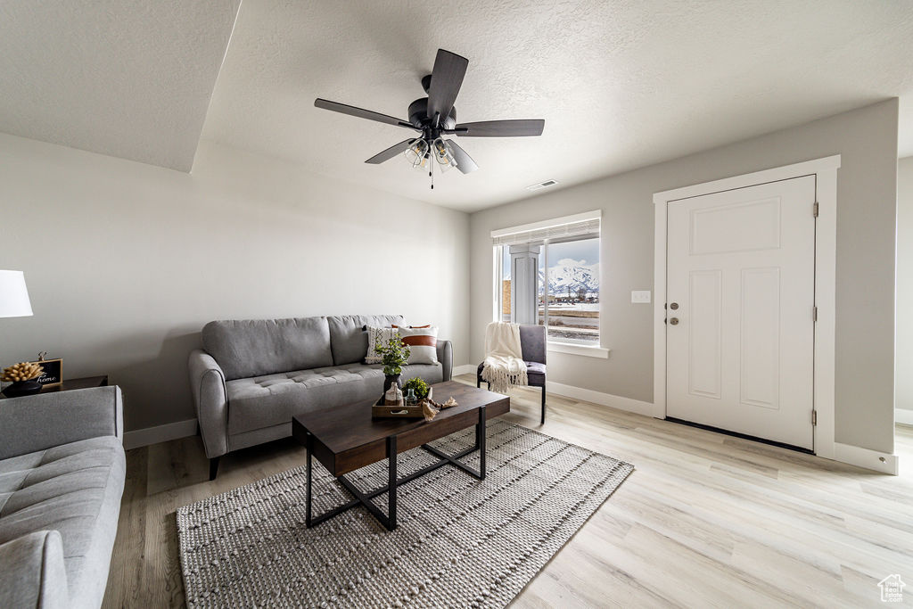 Living area featuring light wood-style floors, a ceiling fan, and a textured ceiling