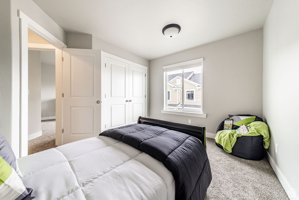 Carpeted bedroom with baseboards and a closet