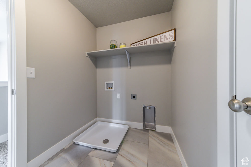 Laundry area featuring hookup for a washing machine, hookup for an electric dryer, and light tile patterned flooring