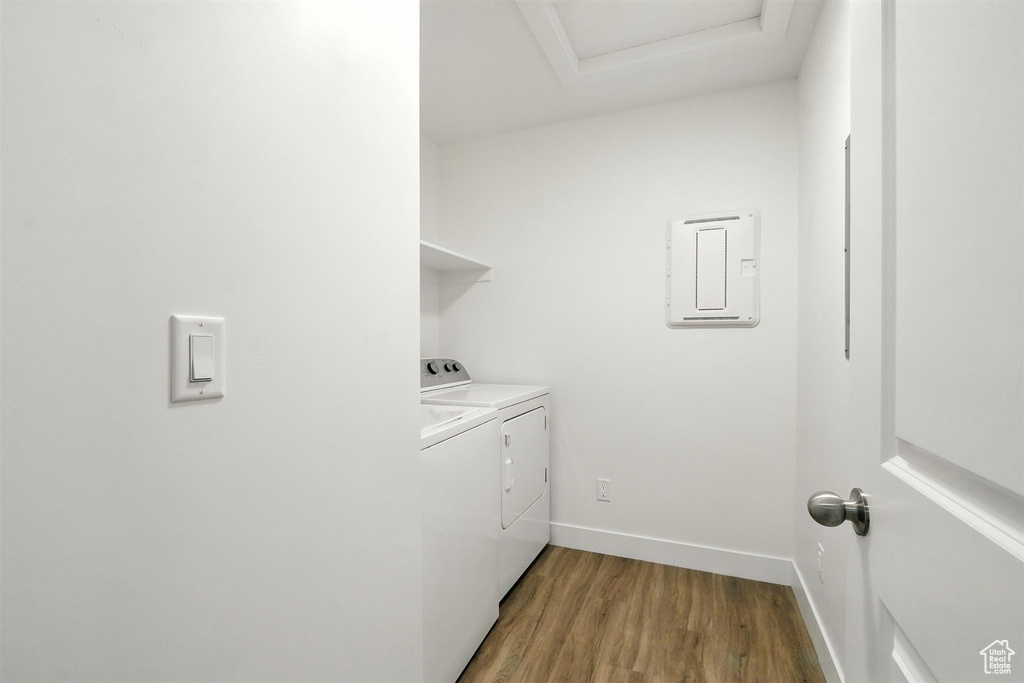 Laundry area with electric panel, independent washer and dryer, light wood finished floors, and attic access