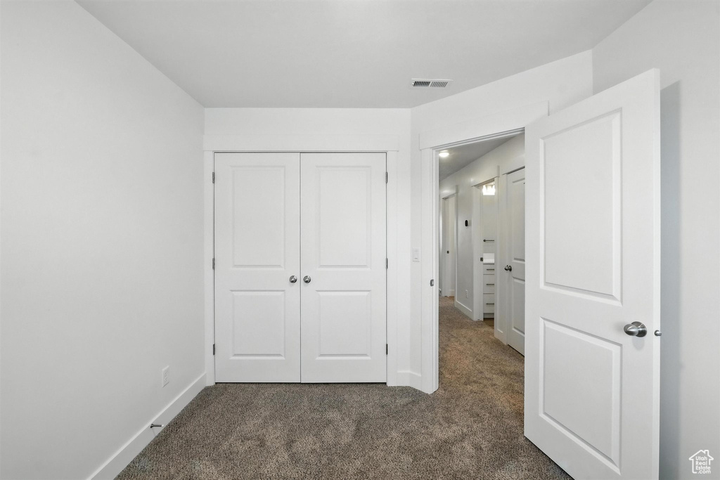 Unfurnished bedroom with dark carpet and a closet