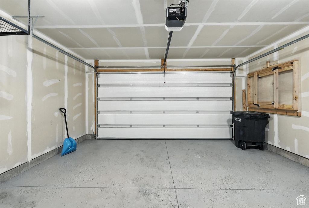 Garage featuring a garage door opener and baseboards