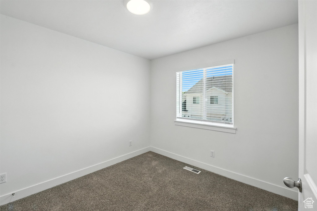Spare room with dark colored carpet and baseboards