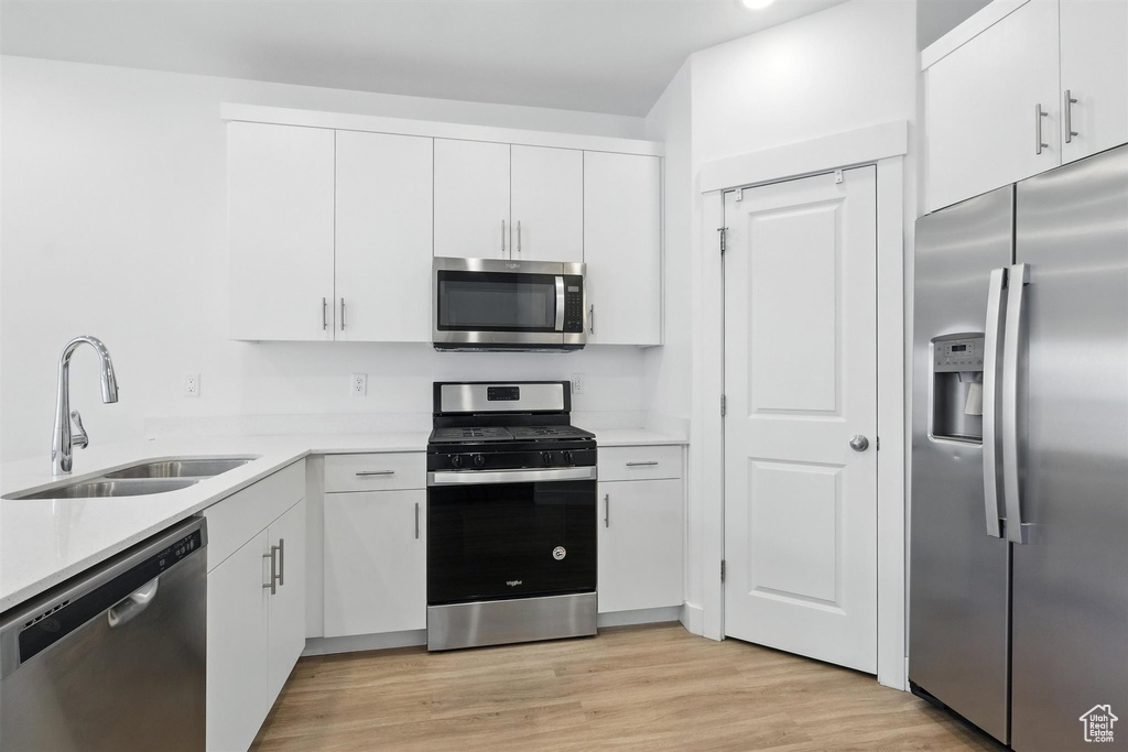 Kitchen featuring stainless steel appliances, light countertops, and white cabinetry