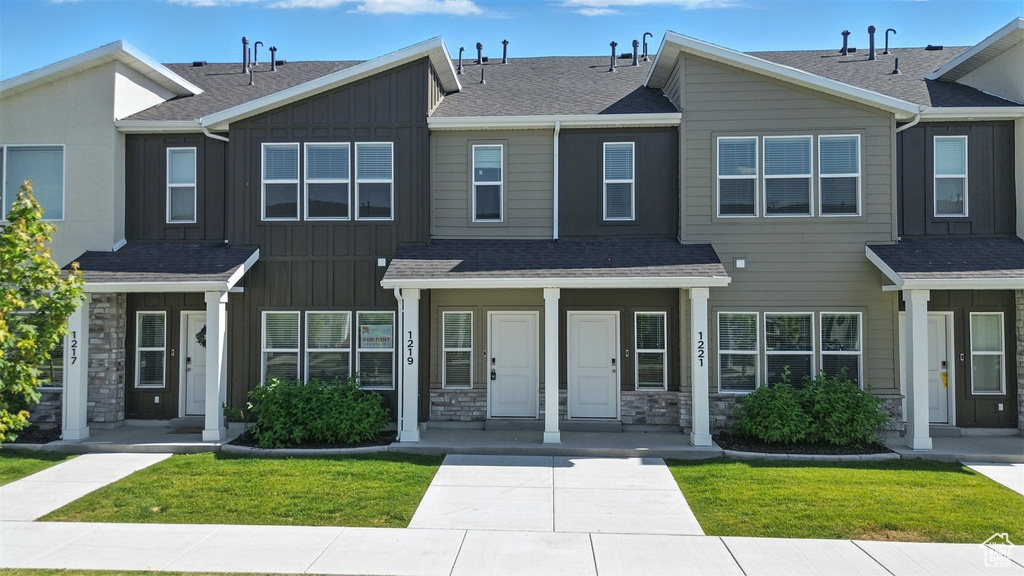 Multi unit property with board and batten siding, stone siding, a shingled roof, and a front lawn