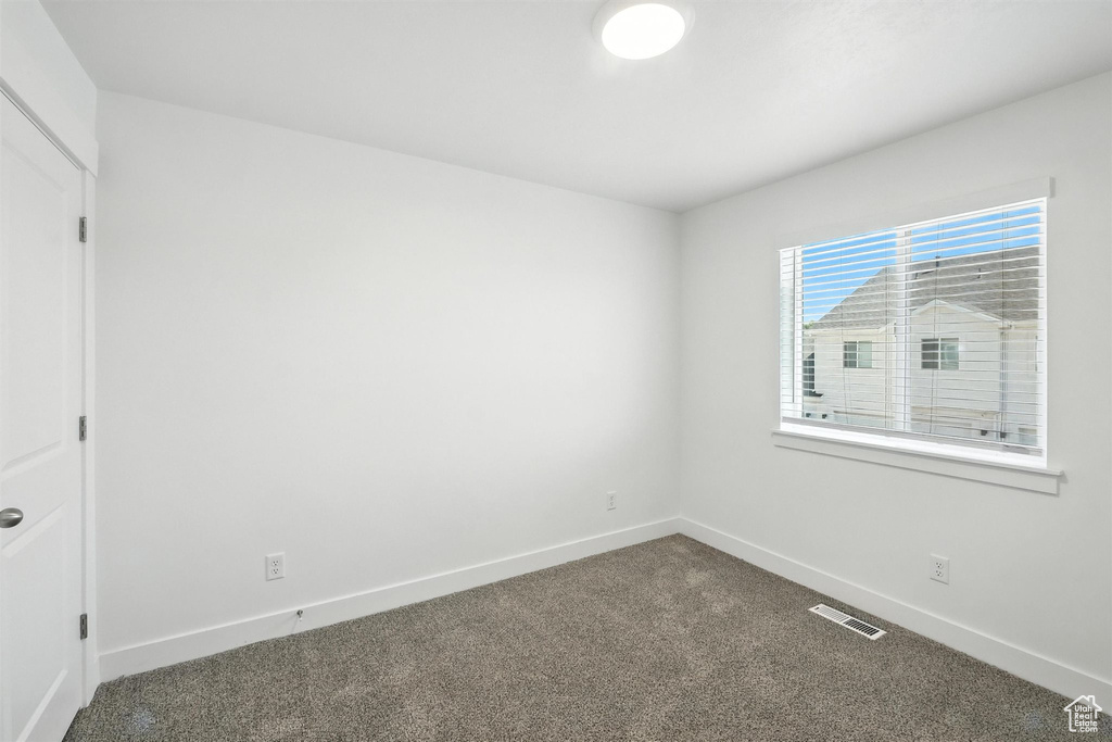 Unfurnished room with dark carpet and baseboards
