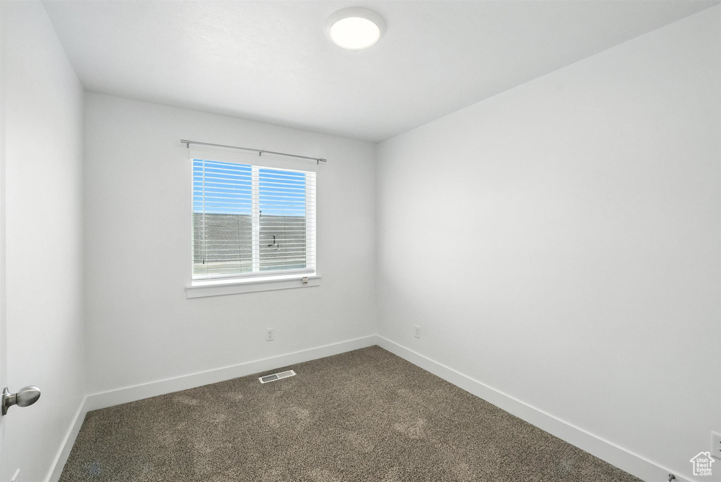 Empty room with baseboards and dark carpet