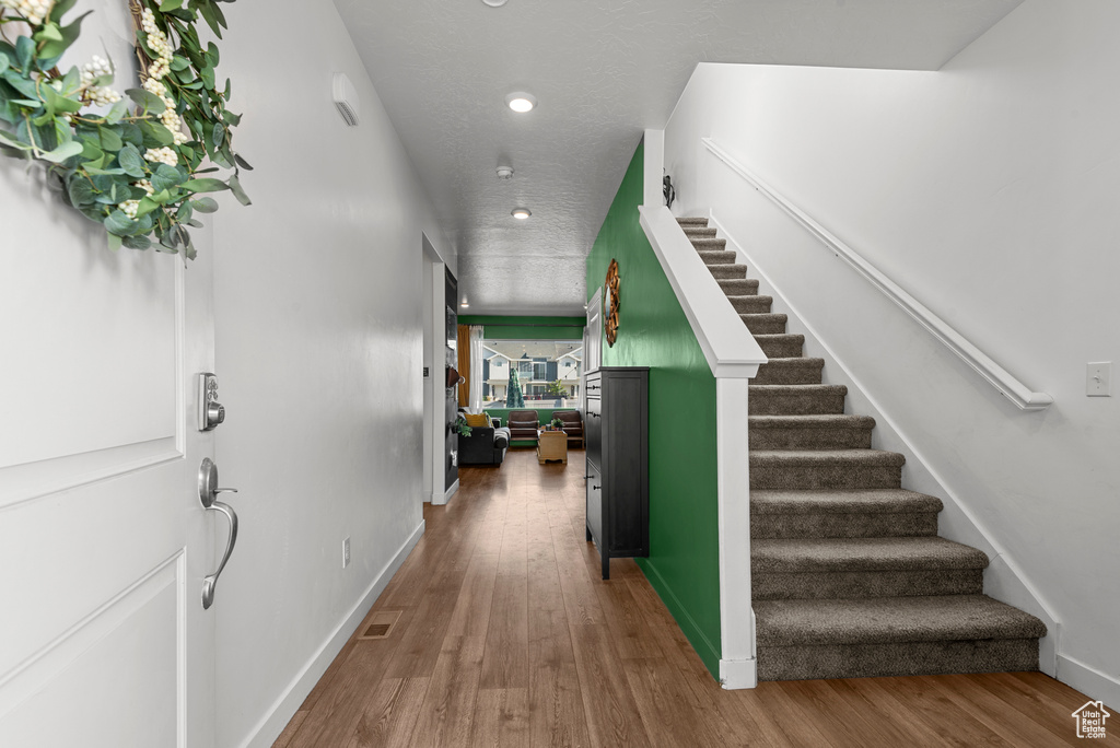 Hallway featuring stairway, recessed lighting, and wood finished floors