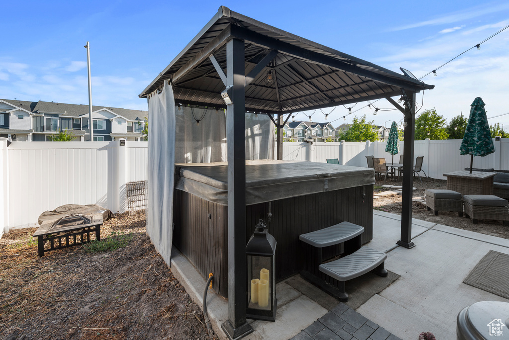 Fenced backyard featuring a hot tub, a patio, a gazebo, a residential view, and outdoor dining space