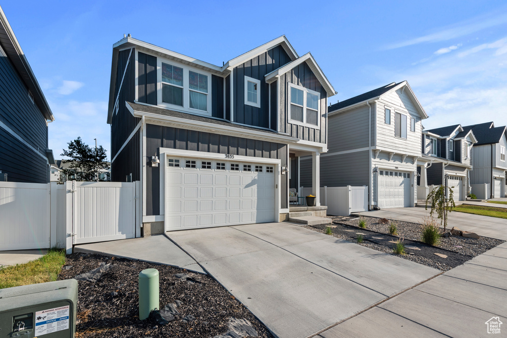 View of front of property with board and batten siding, a garage, and driveway