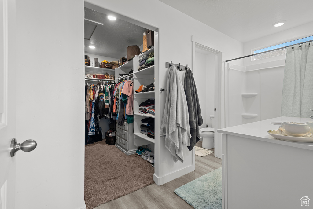 Walk in closet with light wood finished floors and a sink