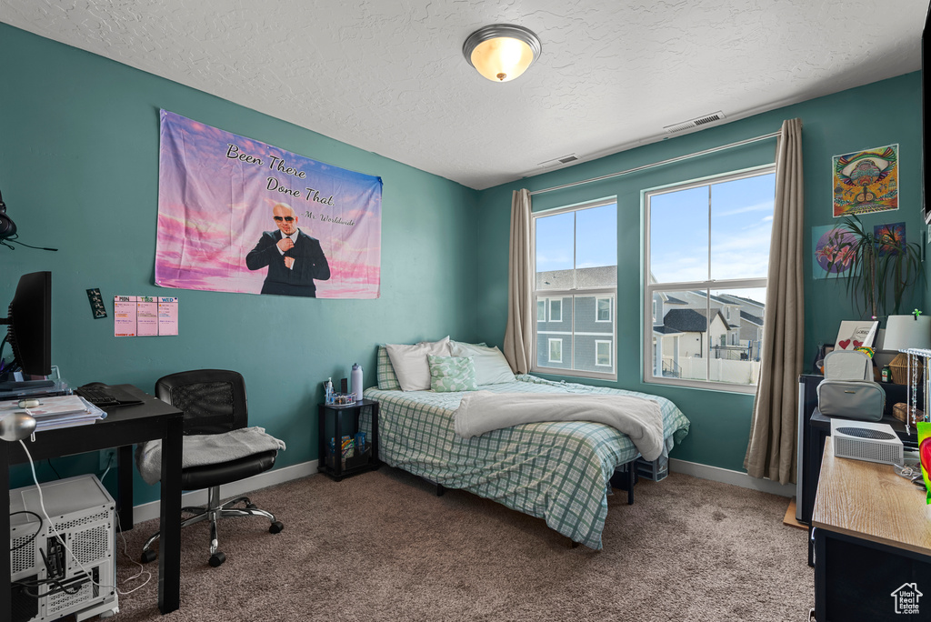Bedroom featuring a textured ceiling, carpet floors, and a desk