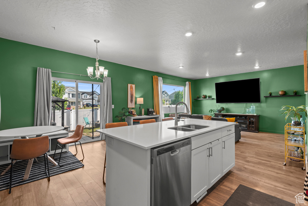 Kitchen with dishwasher, light wood finished floors, light countertops, a chandelier, and white cabinets