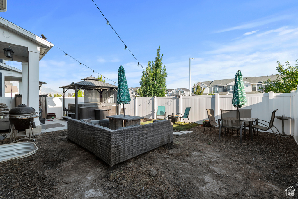 Fenced backyard with a hot tub, grilling area, a gazebo, a patio area, and a residential view