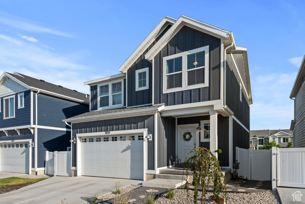View of front of property featuring board and batten siding, a garage, concrete driveway, and a gate