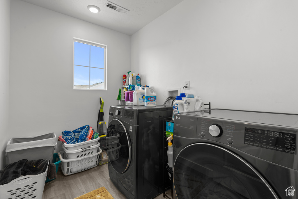 Laundry room featuring washing machine and dryer and wood finished floors