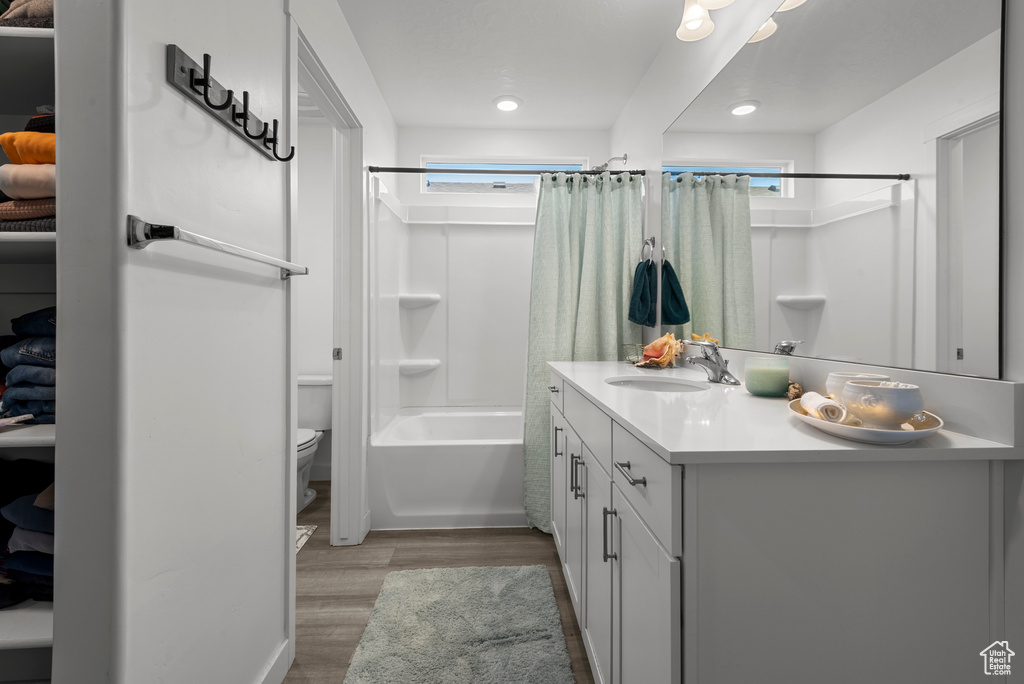 Bathroom featuring vanity, wood finished floors, shower / bath combo with shower curtain, and recessed lighting