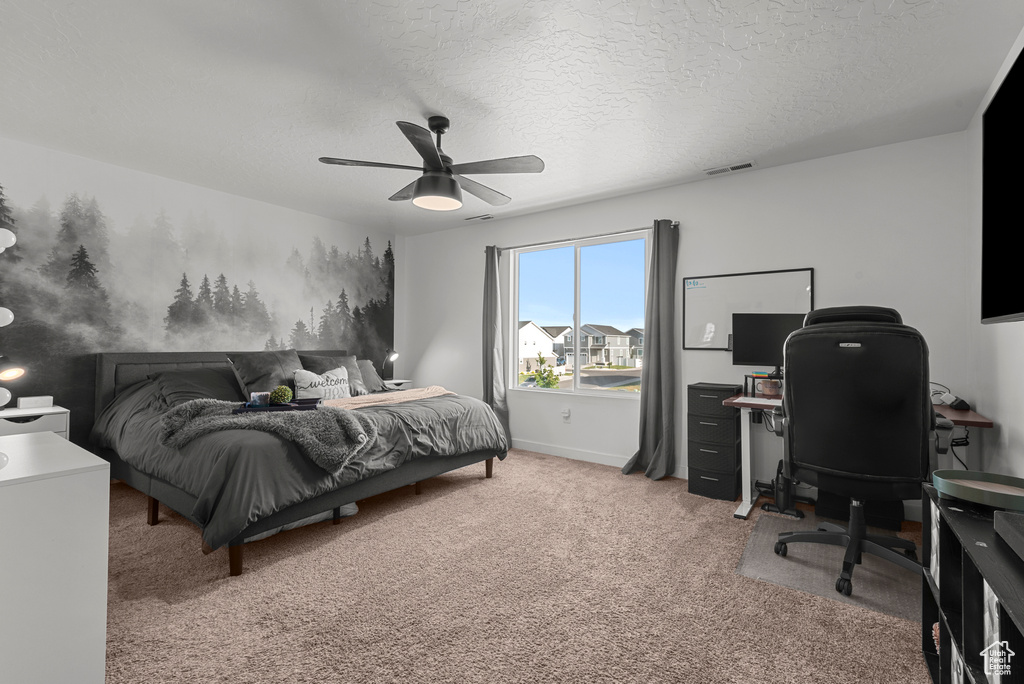 Bedroom with light carpet, an office area, a textured ceiling, and a ceiling fan