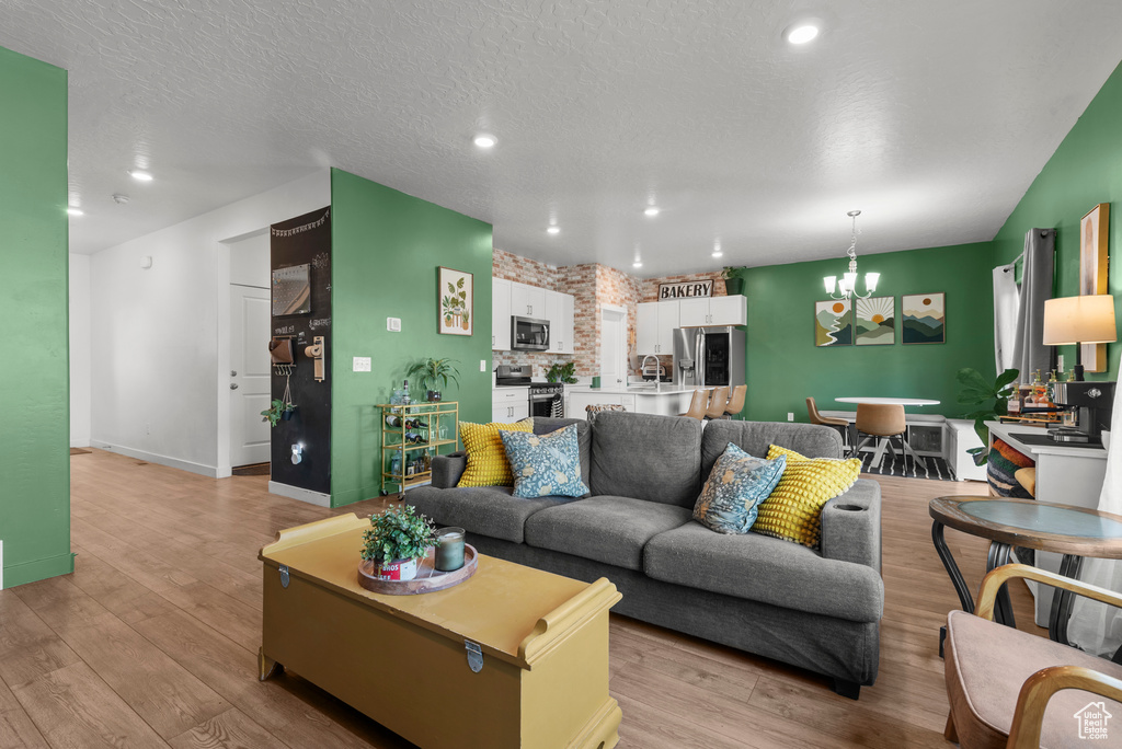 Living room with a chandelier, light wood-type flooring, recessed lighting, and a textured ceiling