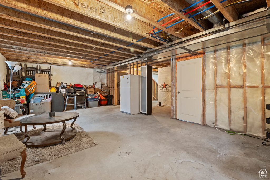 Unfinished basement featuring freestanding refrigerator