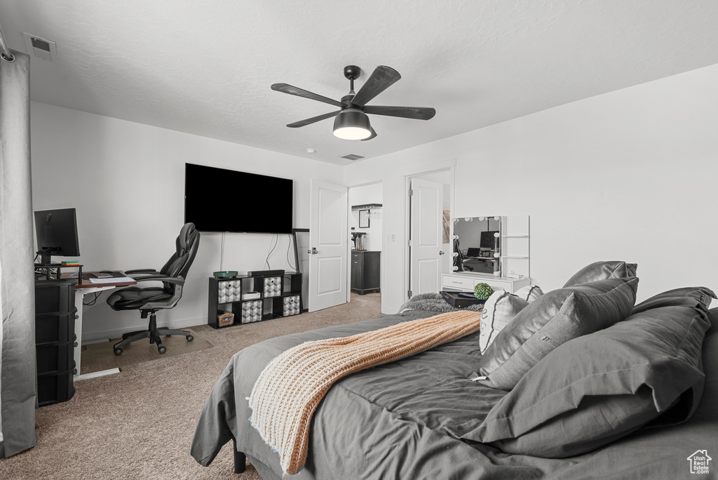 Carpeted bedroom featuring a desk and ceiling fan