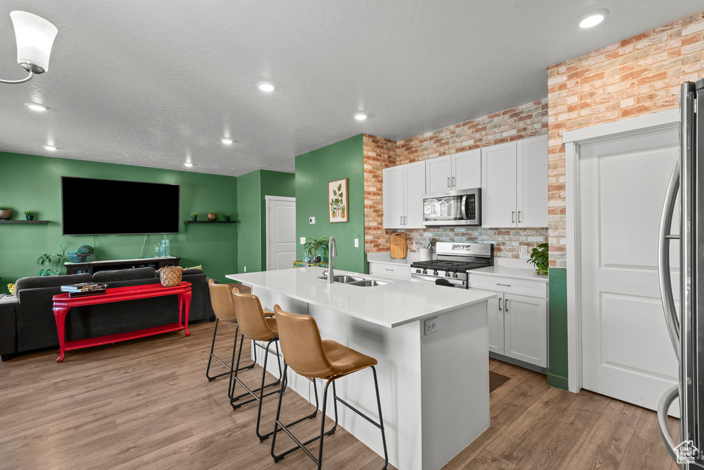 Kitchen featuring stainless steel appliances, a breakfast bar area, white cabinets, light countertops, and recessed lighting