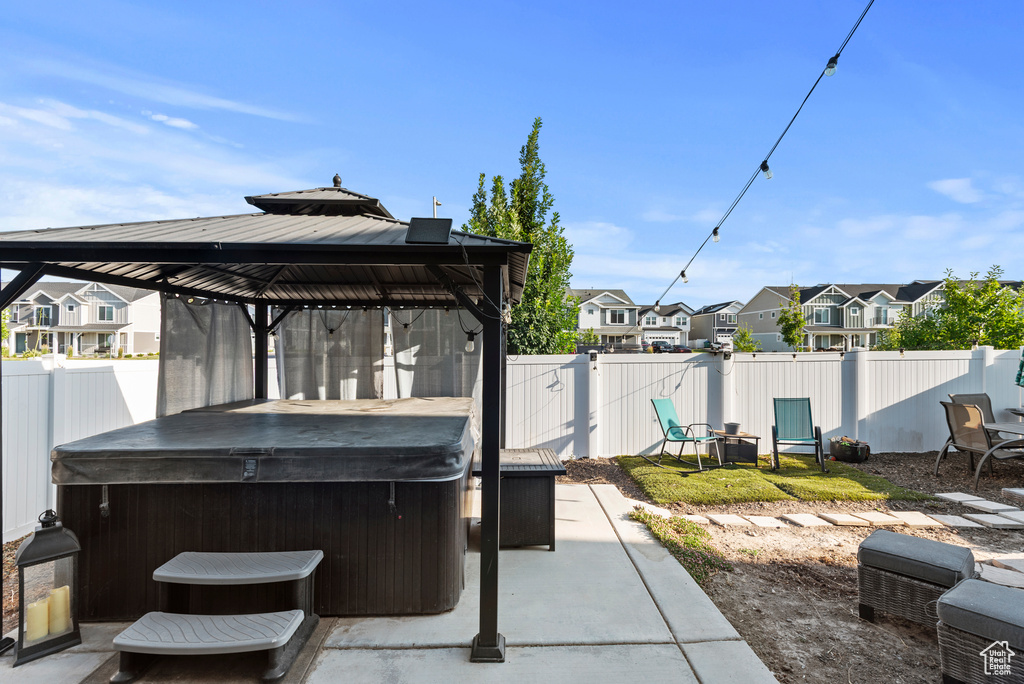 Fenced backyard featuring a hot tub, a gazebo, a residential view, and a patio area