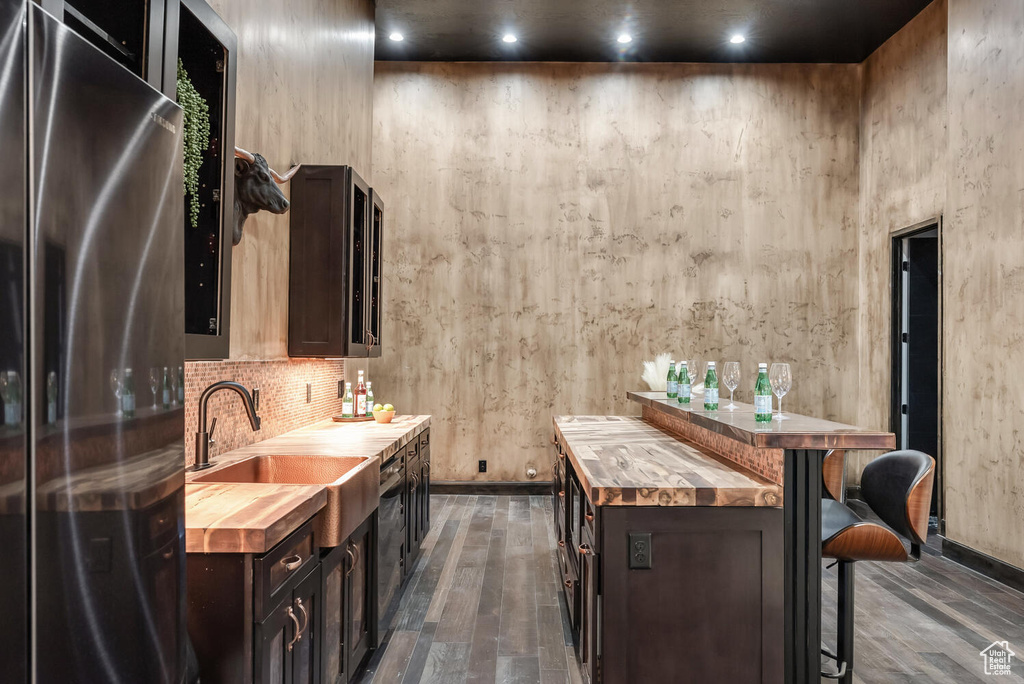 Bar featuring freestanding refrigerator, dark wood-style floors, and tasteful backsplash