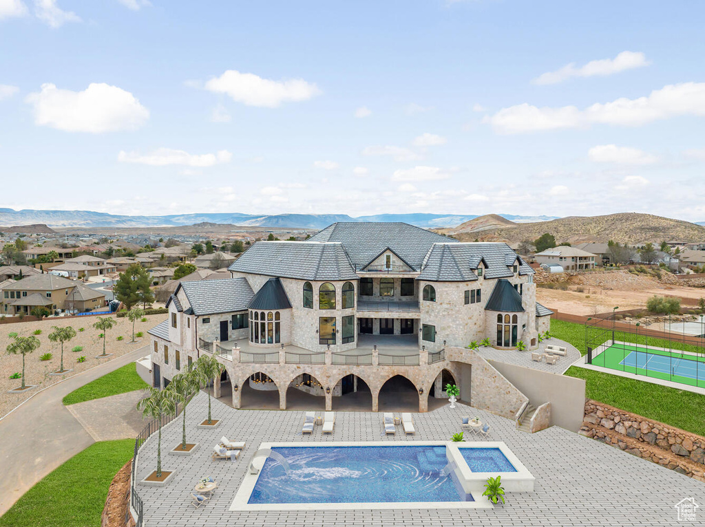 Back of house featuring a balcony, stone siding, a mountain view, and a patio area