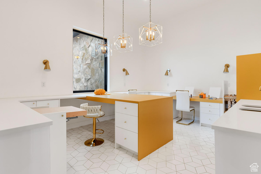 Home office with a chandelier, built in desk, and light tile patterned flooring