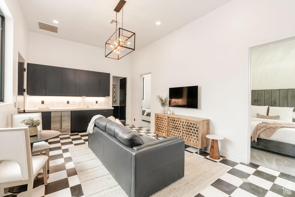 Living room with light floors, a chandelier, recessed lighting, and a towering ceiling