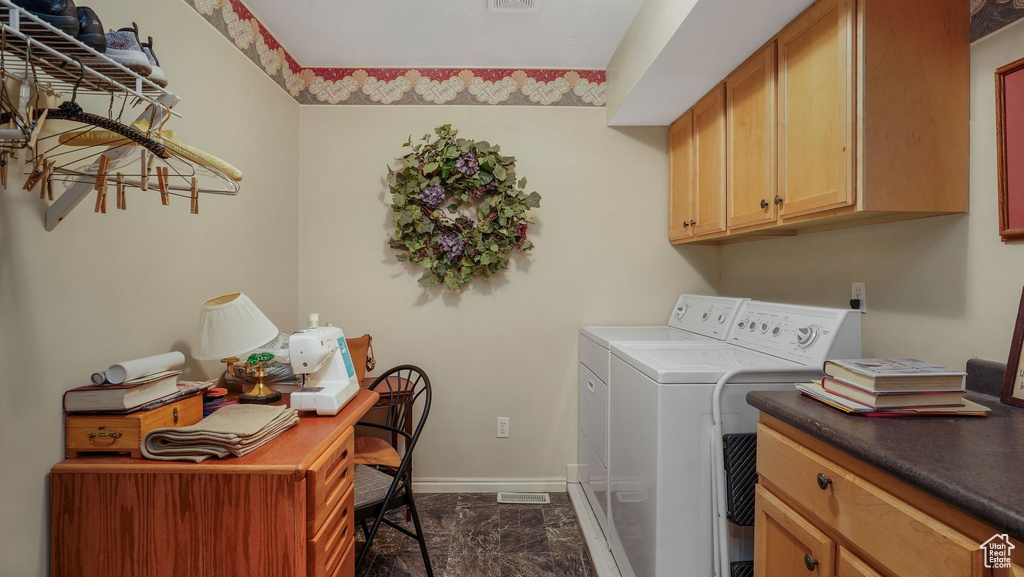 Washroom featuring washer and dryer, cabinet space, dark marble finish floors, and a desk