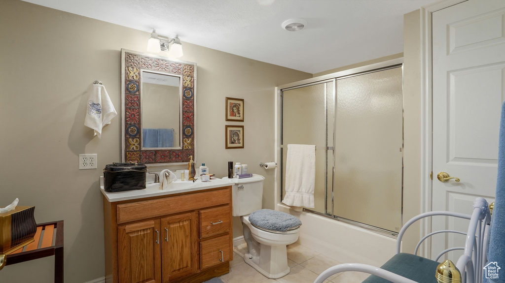 Bathroom with tile patterned floors, vanity, and bath / shower combo with glass door