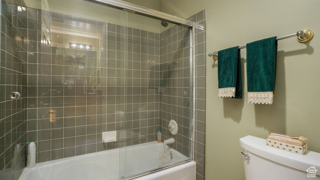 Full bathroom with toilet and bath / shower combo with glass door