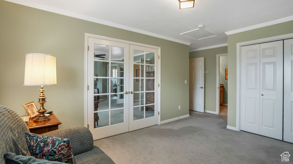 Living area with french doors, attic access, carpet, and ornamental molding