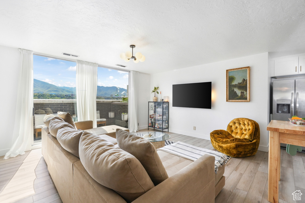 Living area with a textured ceiling, light wood-style flooring, and floor to ceiling windows