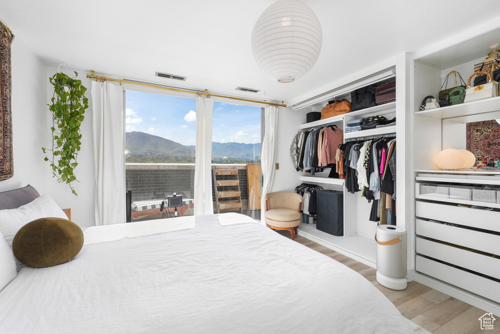 Bedroom with wood finished floors, a mountain view, and a closet