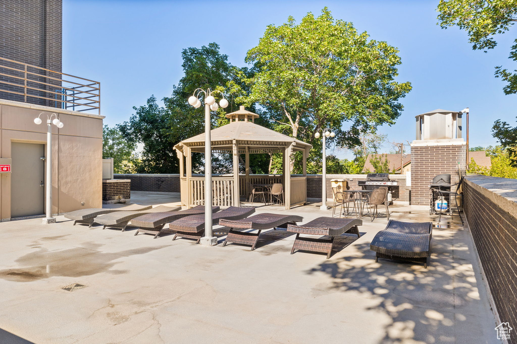 View of patio featuring a gazebo, a grill, and an outdoor brick fireplace