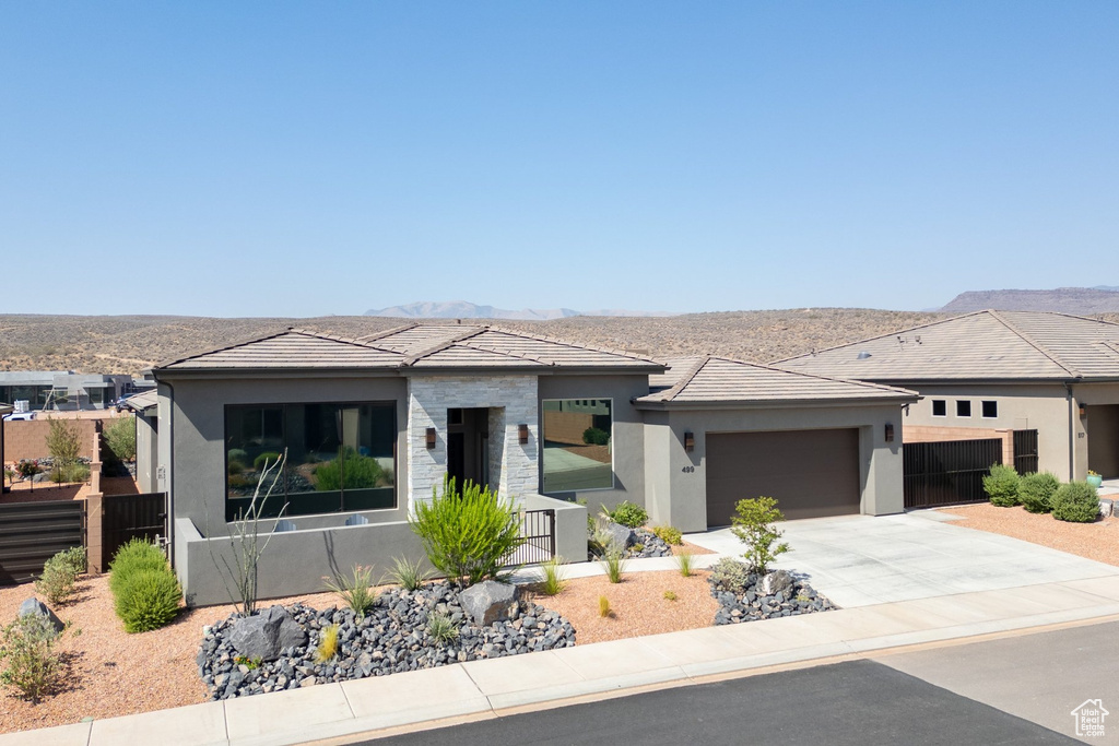 Prairie-style home with stucco siding, a garage, driveway, and a mountain view