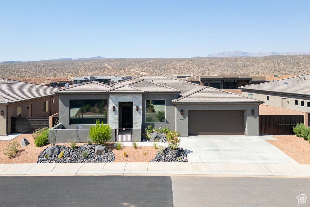 Prairie-style house with an attached garage, stucco siding, a mountain view, and driveway