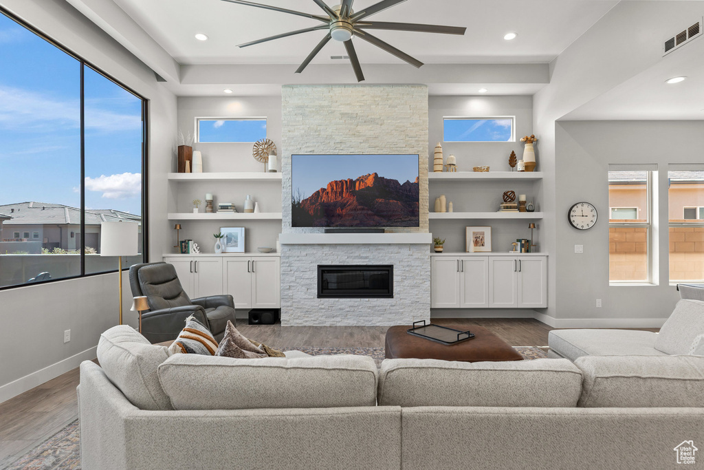 Living area with a fireplace, a ceiling fan, wood finished floors, recessed lighting, and built in features