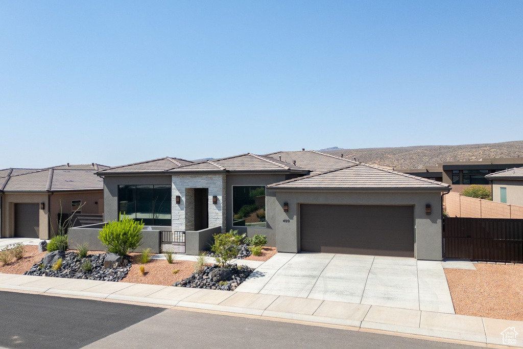 View of front of house with an attached garage, stucco siding, a tile roof, and concrete driveway