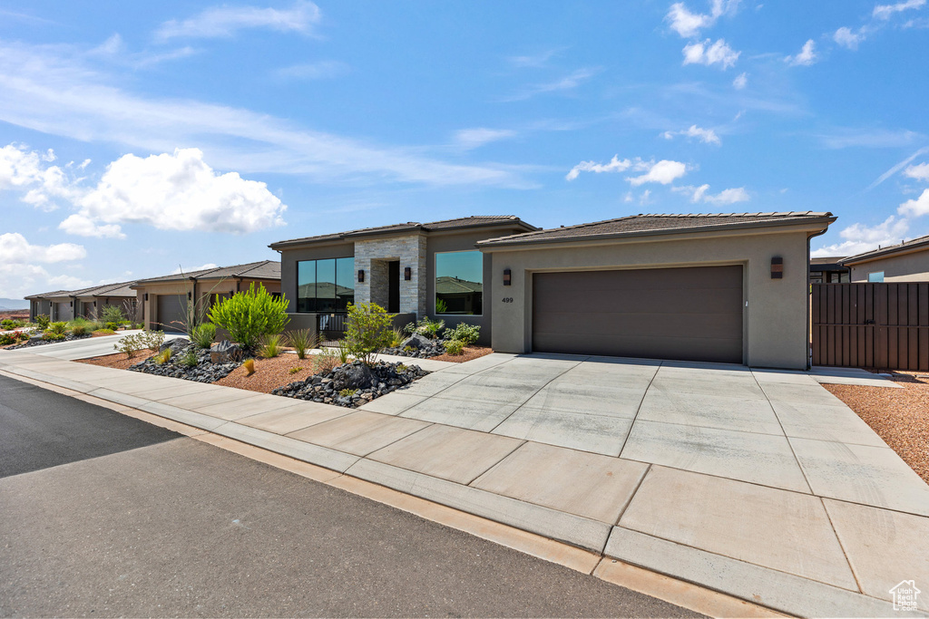 View of front facade with stucco siding, concrete driveway, an attached garage, and a tile roof