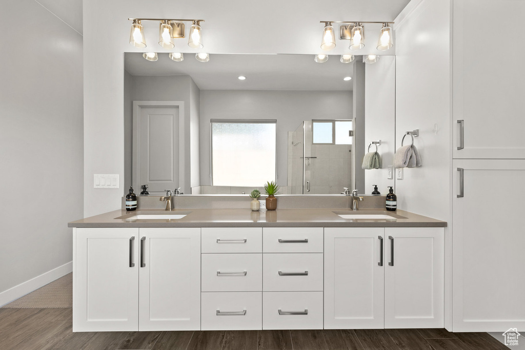 Bathroom featuring double vanity, a stall shower, and wood finished floors